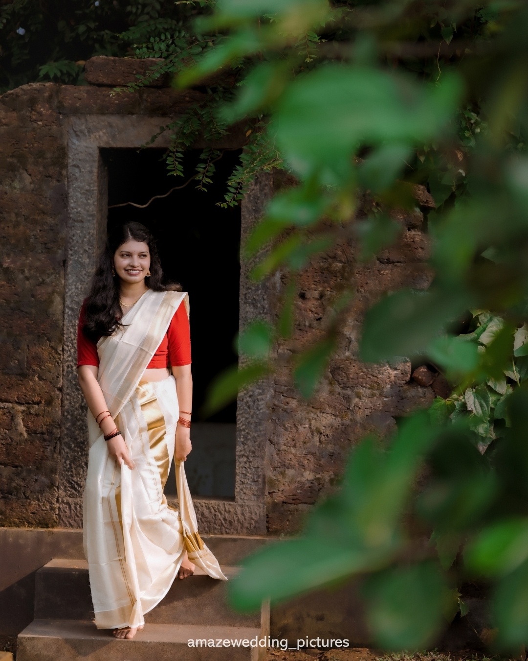 A bride in an ivory sari standing in a historic doorway