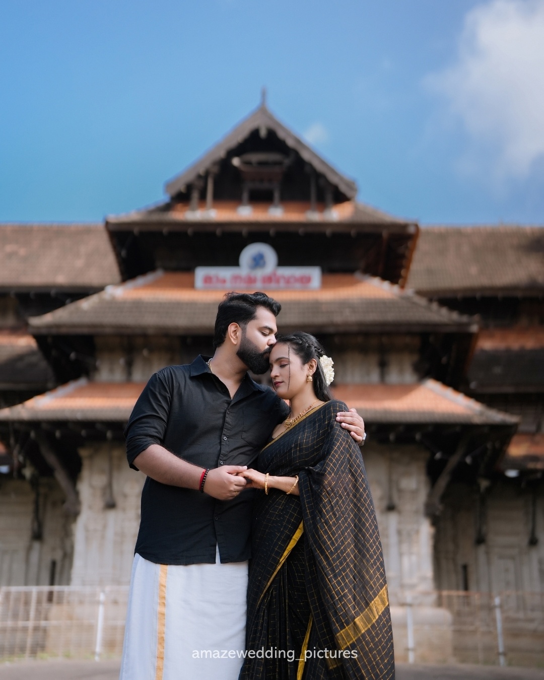 A couple sharing a quiet moment before traditional Kerala architecture