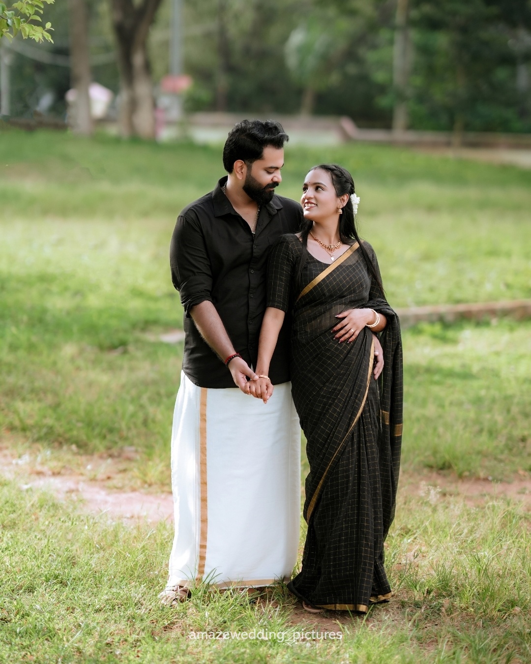 A couple walking hand in hand through a green outdoor setting